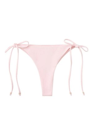 Femme en bikini rose clair avec un paréo en crochet debout près d'une piscine, portant un collier pendentif en spirale et les cheveux mouillés.