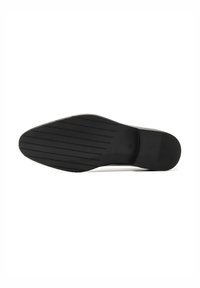 Semelle de chaussure noire avec des rainures horizontales sur l’avant-pied et un talon lisse, présentée sur fond blanc.