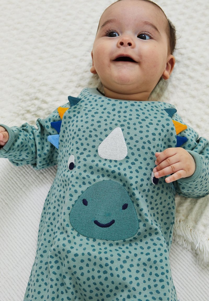 Body a maniche lunghe per neonati in teal con un design di dinosauro, caratterizzato da spine colorate, un motivo a pois e un volto sorridente ricamato sulla pancia.