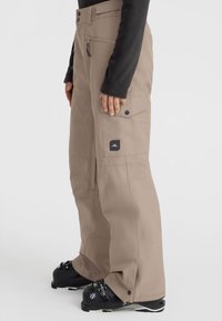 Beige cargo pants with a relaxed fit, multiple pockets, zip closure, and adjustable hem. Durable fabric with a smooth texture.