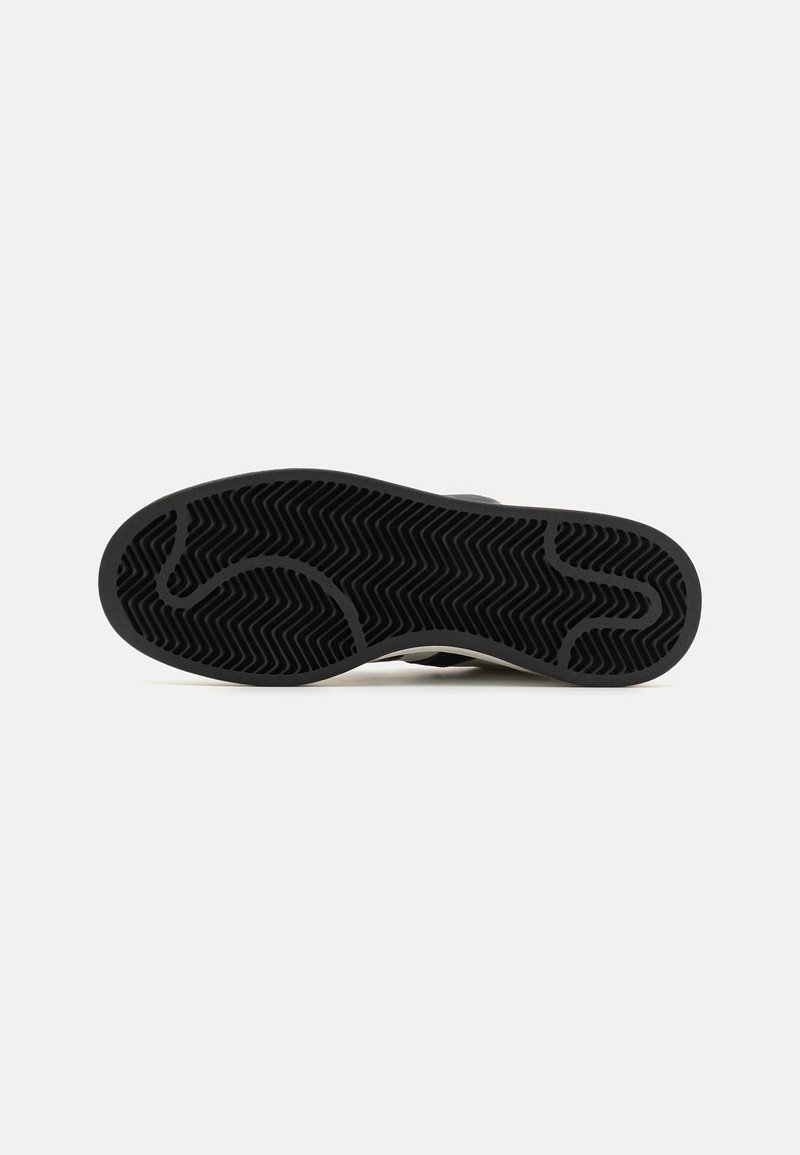 Semelle de chaussure en caoutchouc noir avec un motif de semelle en chevron, design à bout arrondi et légère courbe sur le côté, mettant en valeur une surface texturée.