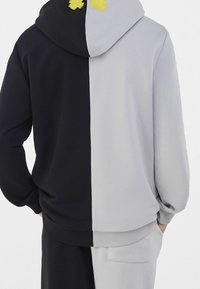 Hoodie med en delad design där navy är på ena sidan och ljusgrå på den andra. Mjukt tyg, ribbad nederkant och fickdetalj.