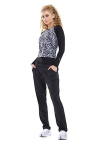 Top a maniche lunghe con stampa leopardata in bianco e nero abbinato a pantaloni jogger neri. L'outfit presenta un tessuto morbido e una vestibilità comoda.