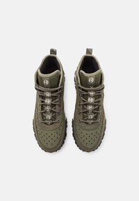 Baskets vertes en maille et daim avec perforations, bout rond, lacets texturés et semelle en caoutchouc noir. Présente un logo sur la languette.