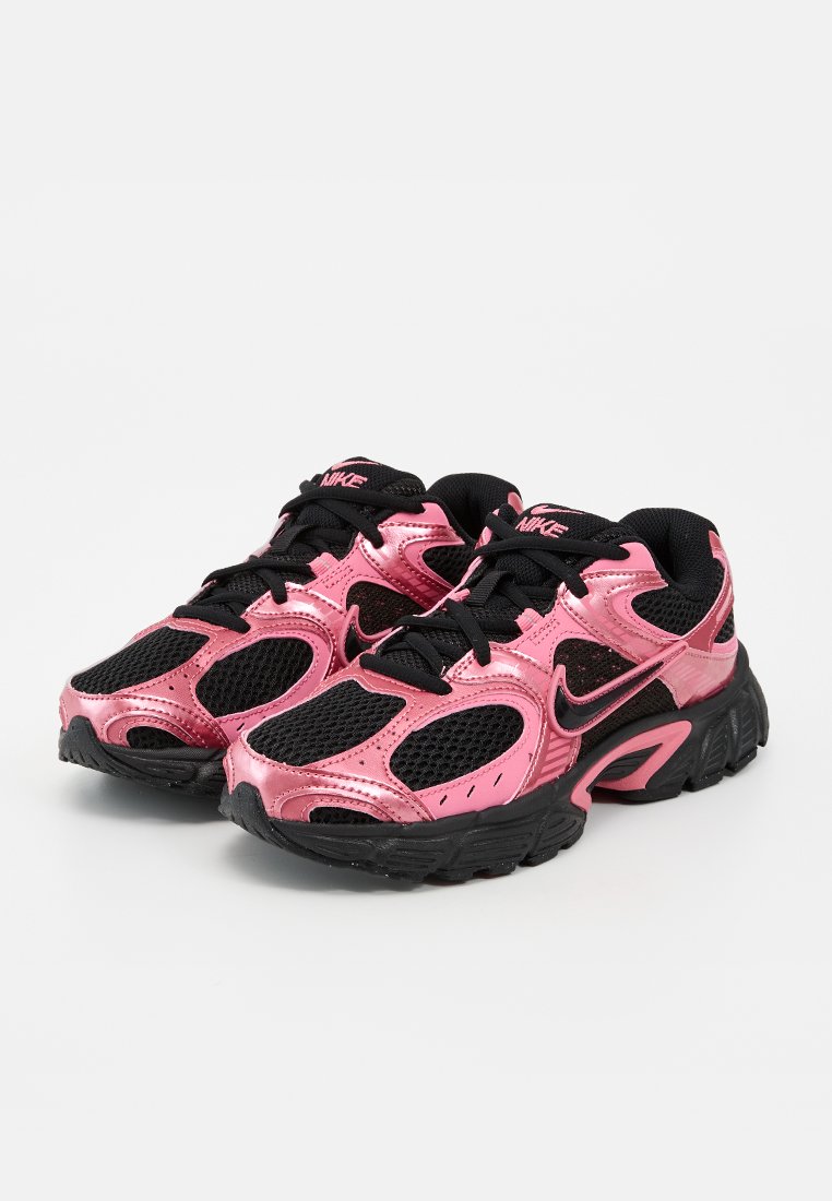 Paire de chaussures de sport noires et roses brillantes avec des semelles épaisses et des lacets noirs, affichant le logo Nike sur les côtés et les languettes.