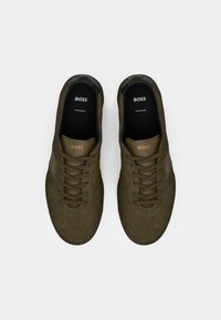Olivengrønne sneakers lavet af ruskind med en glat finish. Funktioner inkluderer klassiske snørebånd, let branding på siden og en kontrastsål.