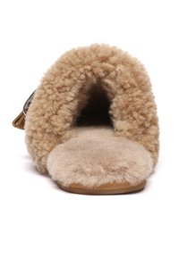 Beige slipper with a fluffy, textured fur lining. Open design with a soft footbed and a smooth outsole. Features an attached strap for adjustment.