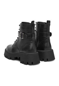 Czarne skórzane botki za kostkę z masywną platformą, sznurowanym przodem, bocznym zamkiem błyskawicznym oraz dekoracyjną klamrą na cholewce.