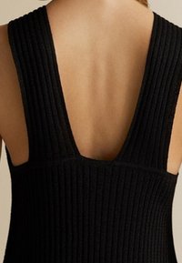 Robe en maille côtelée noire avec un dos en V profond, dotée d'une finition texturée et de larges bretelles.