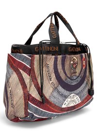 Borsa in tessuto con motivi grafici circolari in rosso, blu e crema; presenta manici neri e dettagli di accento, con branding sui lati.