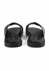 I sandali neri hanno due ampie cinghie, una suola piatta con una leggera texturizzazione e una comoda soletta interna liscia con un discreto dettaglio del logo.