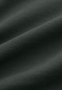Gros plan d’un tissu doux gris foncé avec une texture fine en tricot et des plis délicats.