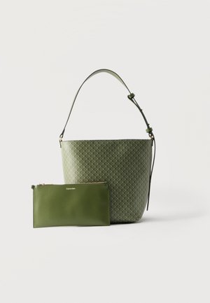 Roheline ämbrikujuline kott geomeetrilise mustriga ja reguleeritava rihmaga, koos sobiva ühevärvilise rohelise tõmblukuga rahakotiga, millel on Calvin Kleini märk.