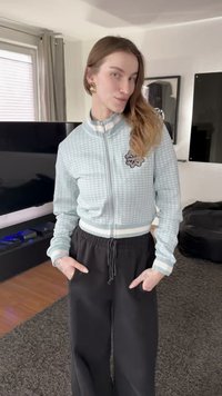 Ανοιχτό μπλε bomber μπουφάν με φερμουάρ, με υφασμένο μοτίβο πλέγματος, λευκές ρίγες και μαύρο παντελόνι με κορδόνια. Διακοσμημένο με ένα μικρό διακοσμητικό έμβλημα.