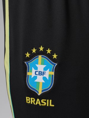 Embleem van het Braziliaanse voetbalteam met vijf gele sterren erboven en de tekst "BRASIL" eronder op zwarte stof met gele en groene strepen.