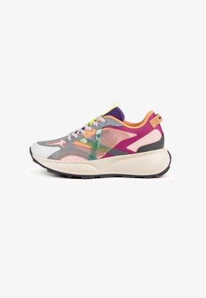 Zapatilla deportiva multicolor con lengüeta de malla púrpura, paneles laterales transparentes, forro melocotón, cordones blancos y púrpuras, y suela blanca gruesa.