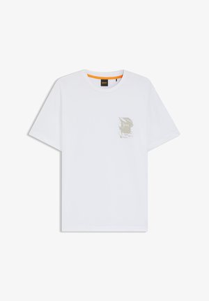 T-shirt de algodão branco com um emblema texturizado verde no lado esquerdo do peito. Decote arredondado e mangas curtas.