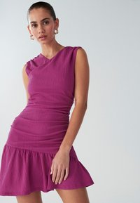 Fuchsia textured dress with a fitted bodice and flared skirt. Features a one-shoulder design and subtle pleating near the shoulder.