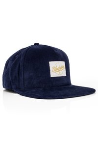 Cappello in corduroy blu navy con visiera piatta e una toppa rettangolare bianca che riporta la scritta "Blackskies" in testo giallo. Tessuto texturizzato con righe verticali.