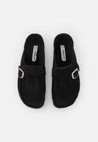 Scarpe slip-on in suede nero con punta arrotondata, dotate di un dettaglio in fibbia argentata e di una morbida fodera interna per il comfort.