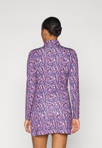 Abito a maniche lunghe di colore viola con un motivo leopardato nero e rosa. Presenta un colletto alto e una silhouette aderente.