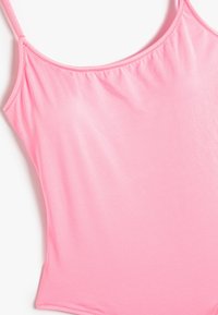 Roze badpak van soepel, rekbaar materiaal met dunne bandjes en geplooide details aan de voorkant.