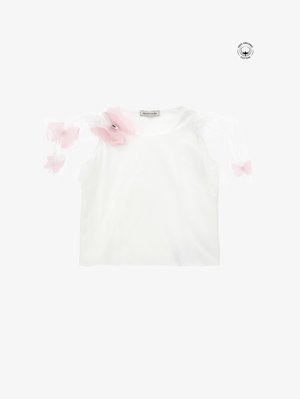 Top de algodón orgánico blanco con una manga abullonada de tul rosa translúcido adornada con acentos florales y un pequeño detalle metálico en el hombro.
