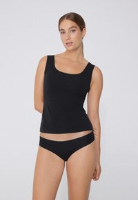 Haut sans manches noir avec un décolleté carré et une coupe ajustée, associé à un ensemble de culottes noires assorties avec une taille lisse et une couverture minimale.