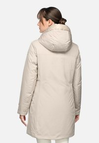 Manteau matelassé beige avec un col haut et une grande capuche, présentant une texture lisse et une coupe droite, conçu pour la chaleur et le confort.