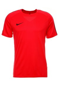 Punainen Nike urheilupaita lyhyillä hihoilla, pyöreällä kauluksella ja mustilla yksityiskohdilla hartioissa. Valmistettu kevyestä, hengittävästä kankaasta.