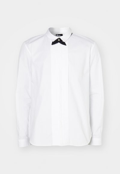 Camicia bianca a maniche lunghe con papillon nero, caratterizzata da un'astuccio frontale con dettagli a costine verticali per tessitura e interesse visivo.