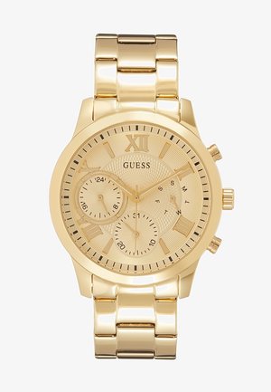 Montre-bracelet Guess ton or avec chiffres romains, trois sous-cadrans pour 24 heures, date et jours de la semaine, et un bracelet métallique lié.