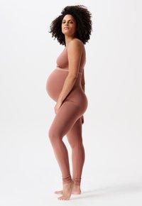 Materniteit activewear set in zachte ribbelstof, met een aansluitend mouwloos topje en hoogtaillelegging in een gedempte rozetint.