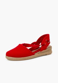 Alpargata roja de lona con punta redonda, tiras entrecruzadas y tacón de cuña envuelto en yute. Textura suave, diseño informal.