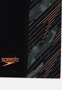 Černé plavecké šortky s texturovaným vzorem zelených a oranžových pruhů a oranžovým logem Speedo, zdůrazňující hladký, elastický materiál.