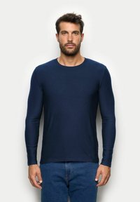 Granatowa koszula z długim rękawem wykonana z gładkiego materiału, z okrągłym dekoltem. Posiada dopasowane rękawy i prosty, minimalistyczny design.