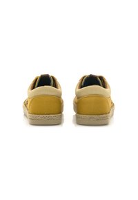Zapatos de tela amarillos con una parte trasera de lona color beige y suela de yute trenzado. Presentan una lengüeta en el talón y un forro interior azul en contraste.