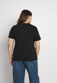 Černé tričko s krátkým rukávem a kulatým výstřihem, vyrobené z měkké látky. Zadní strana má hladkou texturu a jemný štítek s logem poblíž lemu.