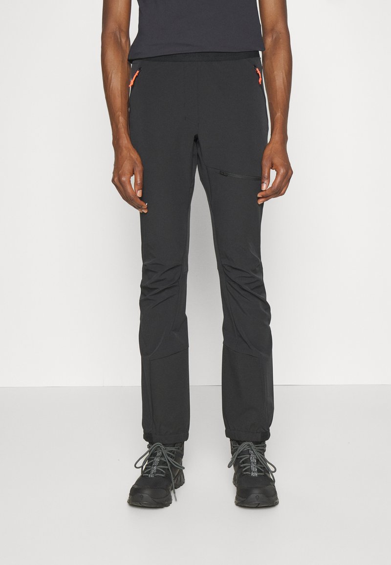 Svart utendør bukser laget av elastisk materiale, med glidelåslommer og orange detaljer, samt en slim fit design. Teksturert overflate.
