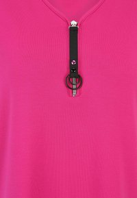 Fuchsia short-sleeve top with a half-zip closure featuring a black zipper and ring pull, smooth texture, and a simple design.