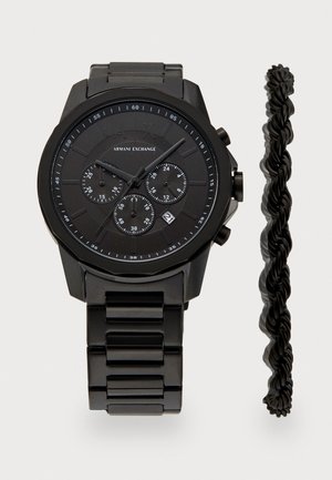 Czarny zegarek ze stali nierdzewnej z teksturowanym cyferblatem, trzema subcyferblatami, wyświetlaczem daty oraz czarną zakręconą bransoletą obok.