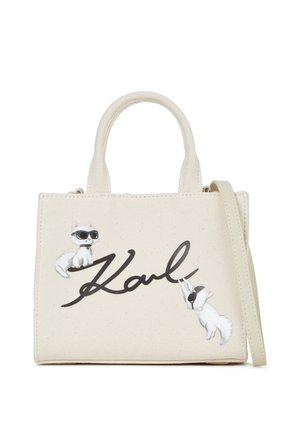 Borsa a mano in cotone color avorio con due applicazioni decorative di gatti. Presenta una firma nera "Karl" e una tracolla rimovibile per maggiore versatilità.