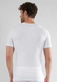 White short-sleeve t-shirt made of lightweight fabric, featuring a fitted design and a round neckline. Smooth texture with minimal detailing.