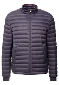 Giacca puffer blu navy con cuciture orizzontali, colletto alto e zip frontale. Presenta polsini elasticizzati e un piccolo logo ricamato sul petto.