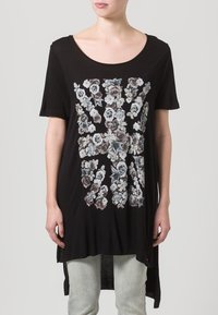 Černá tunika s krátkým rukávem s květinovým designem union jack v tlumených barvách. Vyrobena z měkké látky, má volný střih a delší zadní část.