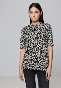 Tričko s krátkým rukávem v leopardím vzoru v béžové a černé barvě, s kulatým výstřihem a volným střihem. Měkký materiál s mírným elastickým efektem.