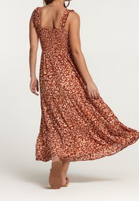 Robe maxi en imprimé animal orange et crème, avec des bretelles à volants et un corsage smocké, agrémenté d'une jupe à volants.