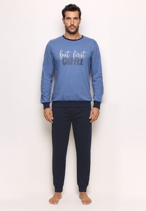 Sweatshirt bleu à manches longues avec le texte "mais d'abord, du café", associé à un pantalon marine foncé. Les deux articles présentent une texture douce et lisse.