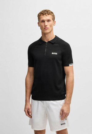 Polo nero a maniche corte, con colletto zip, texture a costine, logo "BOSS" bianco e dettagli a righe sulle maniche.