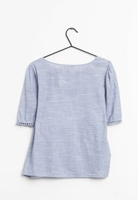 Top in misto lino azzurro chiaro con scollatura ampia, maniche a tre quarti e decorazione con pompon ai polsini; finitura texturizzata.